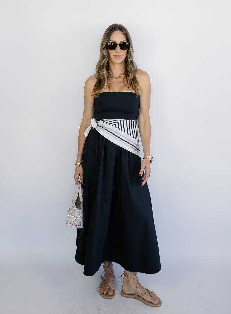 Model wearing a black strapless midi dress with a striped sash